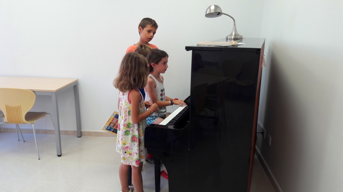 Tres dels alumnes, en una pràctica amb el piano