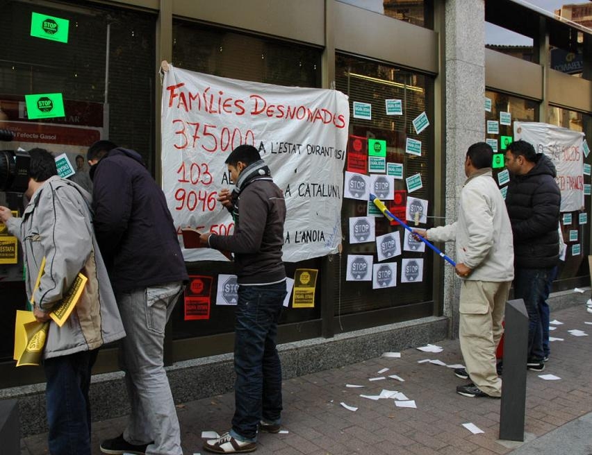 Membres de Pah Anoia enganxant adeshius a l'oficina del Banc Popular